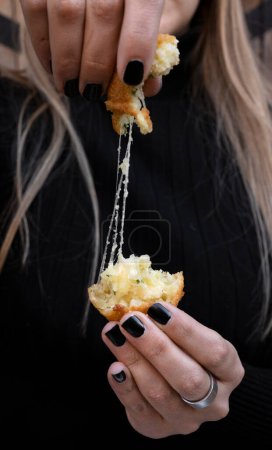 Comida para dedos. Vista de cerca de una mujer estirando el queso de una croqueta de patata y mozzarella en rodajas. 