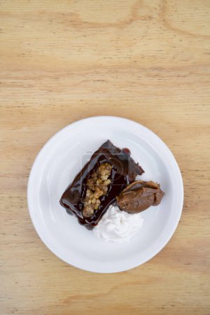 De délicieux desserts. Vue rapprochée d'un flan chocolat doux-amer à la crème vanille et dulce de leche, dans un plat blanc sur la table en bois.