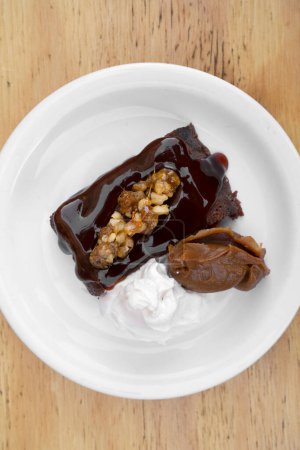 Süße Desserts. Nahaufnahme einer bittersüßen Schokoladenmasse mit Vanillecreme und dulce de leche, in einer weißen Schüssel auf dem Holztisch.