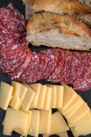 Antecedentes antipasto. Vista superior de un plato con salami en rodajas, queso y pan.
