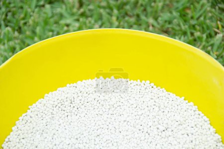Photo for Bucket of white chemical fertilizer in granular format ready to be applied to garden plants. Garden maintenance concept. - Royalty Free Image
