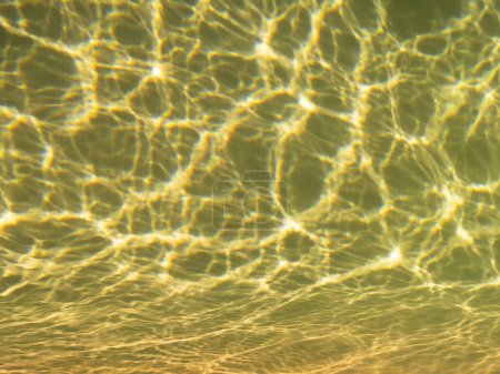 Réflexions des rayons du soleil d'une journée ensoleillée dans une piscine à Javea, Espagne. Image avec une teinte jaune. Vue sur les tuiles, avec des vagues d'eau. Concept de vacances, repos et détente.