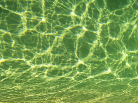 Photo for Reflections of sun rays of a sunny day in a swimming pool in Javea, Spain. Image with green shade. View of the tiles, with waves of water. Concept of vacation, rest and relaxation. - Royalty Free Image