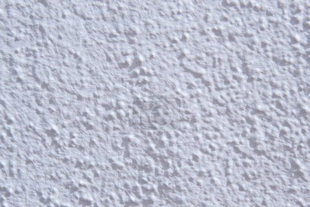 Surface of a white wall with paint drops and relief.