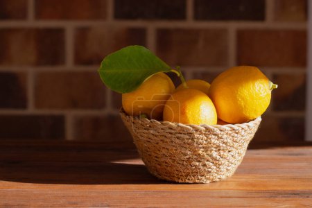 Photo for Home-grown lemons in a wicker basket illuminated by direct sunlight - Royalty Free Image