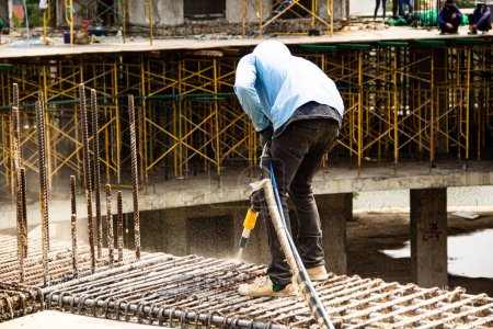 Téléchargez les photos : Un homme travaillant sablage à la barre d'acier sur la structure du bâtiment - en image libre de droit