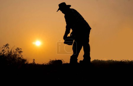 Silhouette of a man lifting a rock wearing a cowboy hat Miners background blur