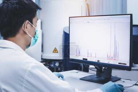Scientist man checks the spectrum of sample analysis by nuclear magnetic resonance spectroscopy, NMR spectroscopy, as shown on a computer monitor in the laboratory.