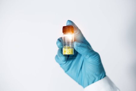 Foto de El primer plano de la mano de Scientist muestra un sólido amarillo pálido en un frasco de un vaso de flavonoides compuesto de extracción y aislamiento en el laboratorio. Sustancias flavonoides se utilizan para medicamentos y medicamentos. - Imagen libre de derechos