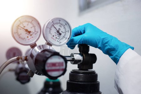 Foto de Primer plano de la mano de un científico, comprobando el gas de un manómetro en busca de un dispositivo de cromatografía de laboratorio durante la investigación. - Imagen libre de derechos