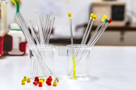 Photo for Yellow and colourless sample solutions were prepared in the NMR glass tubes and placed in a beaker for analysis by the NMR spectroscopy method. Empty NMR glass tubes placed in glassware and tube caps. - Royalty Free Image
