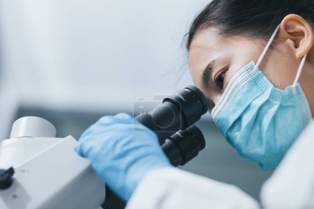 Photo for Closeup shot of female researcher using the microscope to look at culture cells for bioassay of drugs test in the laboratory. Research for pharmaceutical, medicine, and biotechnology development. - Royalty Free Image