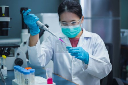 La mujer científica utiliza una micropipeta con preparación de muestras de un tubo de ensayo de solución madre en el laboratorio para bioensayar células in vitro en placas de Petri de vidrio. Medicinal, Medicina, investigación.