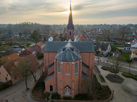 Photo for Emblem, Ranst, Belgium, 15th of February, 2023, Sint-Gummaruskerk, church of saint Gummarus, in the voortstraat of the Little village of Emblem, in the Antwerp area aerial photo during morning sunrise - Royalty Free Image