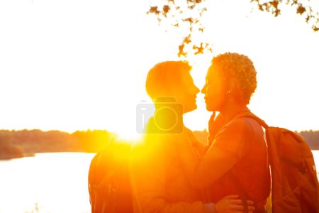 Photo for Close up portrait of a beautiful young interracial couple waiting to kiss passionately in their traveling time against a romantic sunset light. Arab man kissing with a caucasian woman. High quality - Royalty Free Image