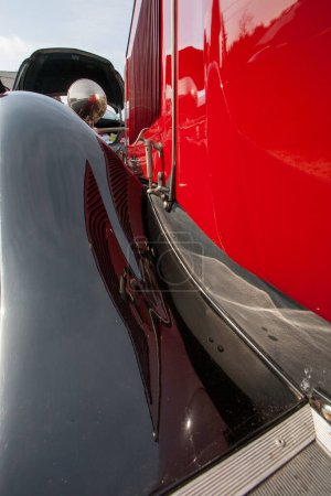 Photo for The image captures a striking angle of a classic car, showcasing the polished black and vibrant red paintwork. The reflection on the gleaming surfaces reveals not just the cars sleek design but also - Royalty Free Image