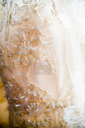 Téléchargez les photos : Ce gros plan détaillé met en valeur la dentelle complexe d'une robe de mariée, mettant en valeur le savoir-faire délicat de la broderie. Perles et paillettes sont entrelacées dans le tissu, ajoutant un subtil - en image libre de droit