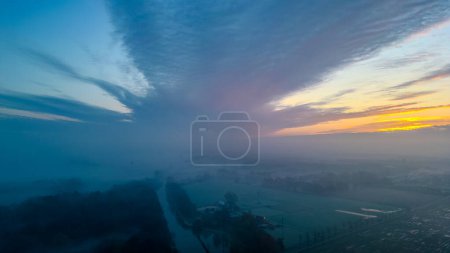 Foto de Una vista aérea captura el momento del amanecer, donde los soles primera luz suavemente adorna el horizonte. El cielo, un lienzo de azules suaves, naranjas cálidas y púrpuras, se extiende majestuosamente por encima de un despertar - Imagen libre de derechos