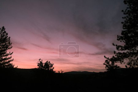Foto de Una imagen evocadora que captura los momentos tranquilos del crepúsculo mientras el día da paso a la noche. El cielo, pintado en tonos suaves de rosa y lavanda, se oscurece gradualmente hacia el marco superior, insinuando - Imagen libre de derechos
