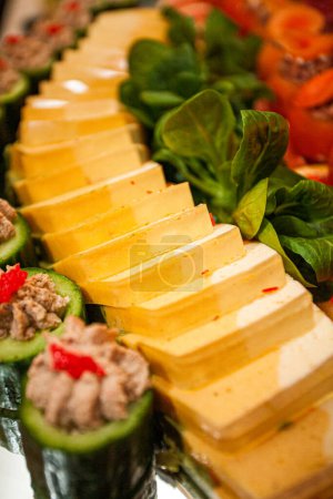 Photo for This image captures a meticulously arranged catering spread, featuring a diagonal sequence of uniformly sliced tofu, each piece gently seasoned with a sprinkle of red spices. Adjacent to the tofu - Royalty Free Image