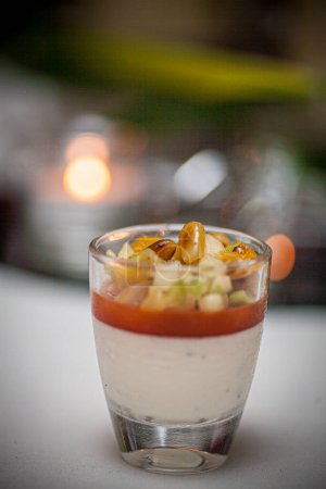 Photo for This image captures the sophisticated presentation of a verrine appetizer, carefully layered in a clear glass. The culinary creation features distinct layers of what appears to be a creamy base, a - Royalty Free Image