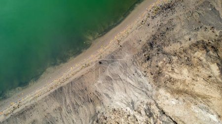 Téléchargez les photos : Cette photographie aérienne saisit le contraste saisissant entre les teintes verdoyantes d'un rivage et les terres stériles adjacentes. La ligne de démarcation claire où la végétation rencontre le sol sec et érodé - en image libre de droit
