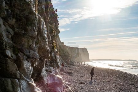 Photo for A striking image that tells a story of exploration and adventure along a rugged cliffside. The focus here is on the figure walking parallel to the cliffs face, which is bathed in sunlight - Royalty Free Image