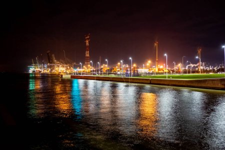 Foto de Una atractiva escena nocturna se desarrolla en el Puerto de Amberes, donde las luces artificiales crean un vibrante tapiz contra el cielo oscuro. El reflejo de las luces en el agua añade una capa de profundidad y - Imagen libre de derechos