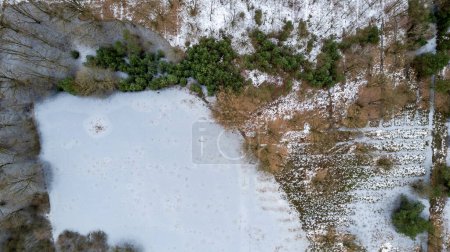 Photo for An overhead perspective captures the transition from winter to spring as snow retreats from a variegated landscape. The image showcases patches of snow interspersed with areas of bare earth and - Royalty Free Image
