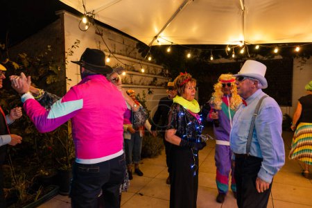 This vibrant image showcases a lively gathering of senior individuals engaged in a festive outdoor celebration. The night is alive with energy as the group, adorned in colorful and eclectic attire