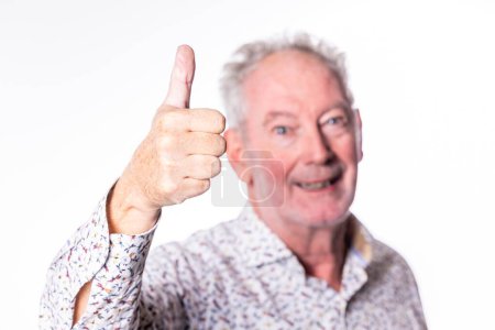 This image features an older man with a joyful expression, giving a thumbs up to the camera. He wears a printed shirt, and his cheerful demeanor exudes positivity and approval. The background is white