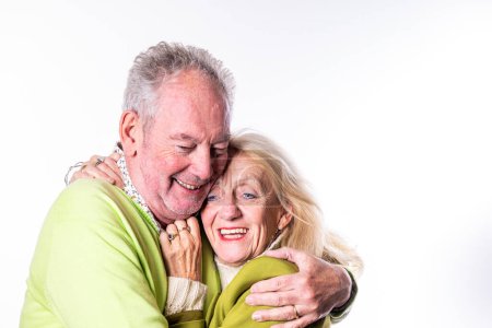 This heartwarming image features an elderly Caucasian couple in a joyful embrace. The man has grey hair and is wearing a light green sweater, while the woman, with her blonde hair, is in a soft olive