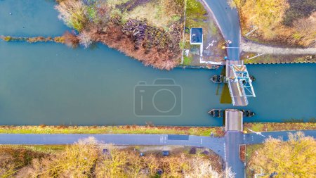 Photo for This aerial image provides a top-down view of a canal lock system, where the calm waters are managed for navigational purposes. The lock, a feat of engineering, sits at the juncture where two roads - Royalty Free Image
