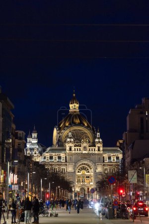 Téléchargez les photos : Anvers, Belgique, le 25 janvier 2024, L'image capture la gare centrale d'Anvers la nuit, sa façade complexe et sa structure bombée luisant contre le ciel sombre. La rue animée De Keyserlei à - en image libre de droit