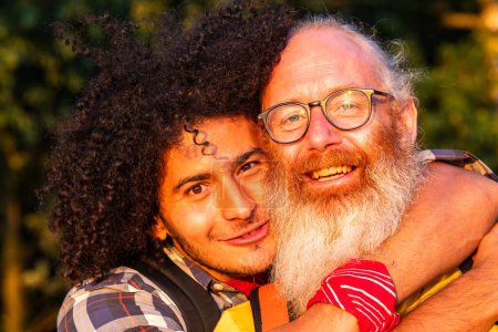 This image captures a heartwarming moment between two men sharing a joyful embrace. The younger man, with his curly hair and bright smile, exudes warmth and happiness. The older man, with a white