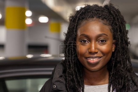 Captured with a bright, engaging smile, this young womans portrait radiates warmth and happiness. Her black dreadlocks provide a lovely contrast to her light toned top and the dark jacket shes wearing