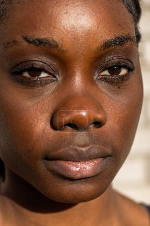 Esta es una imagen de primer plano que se centra en los rasgos faciales de una joven africana. La imagen la captura de la nariz hacia arriba, resaltando sus ojos, cejas y frente. La piel de los sujetos es oscura