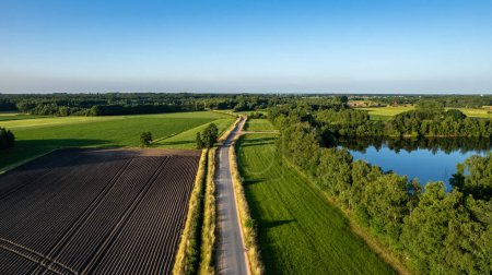 Rural Tapestry: Road Through Fields and Pond in the Countryside. High quality photo