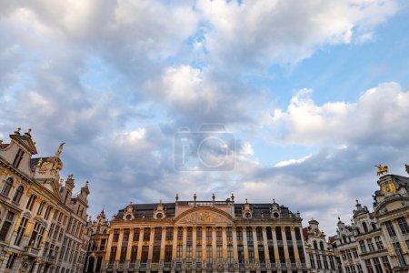 Brussels, Belgium, June 23, 2023, A picturesque ensemble of Grand Places guildhalls under a captivating sky, where the intricate facades are kissed by the soft glow of the fading sunlight. Clouds