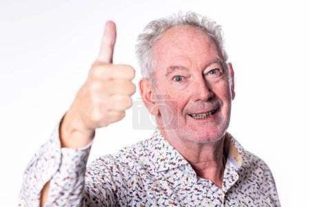 Anciano con pulgares hacia arriba: Un retrato de primer plano de un hombre mayor animado dando un gesto de pulgares hacia arriba, su cara se enciende con una sonrisa amistosa, colocada sobre un fondo blanco y limpio. Animación y aprobación