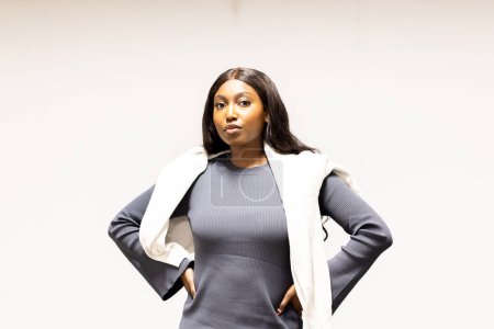 Photo for The image portrays an African American woman exuding confidence and professionalism. Her hands are on her hips, and she stands against a plain background, which puts all the focus on her and her - Royalty Free Image