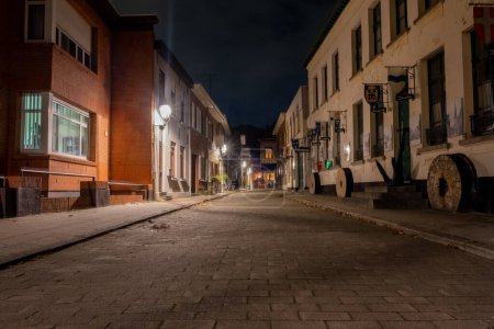 This image offers a nocturnal glimpse into the cobblestone streets of Lillo, Antwerp, as the historic town settles under the nights embrace. The streetlamps cast their light upon the path, creating a