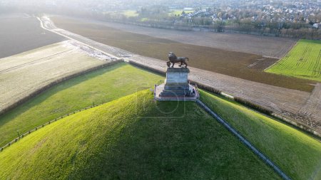 Foto de Waterloo, Bruselas, Bélgica, 25 de febrero de 2024, Esta imagen aérea captura el Lions Mound en el monumento a Waterloo Battlefield. El sol, situado en el horizonte, arroja un cálido resplandor a través de la - Imagen libre de derechos
