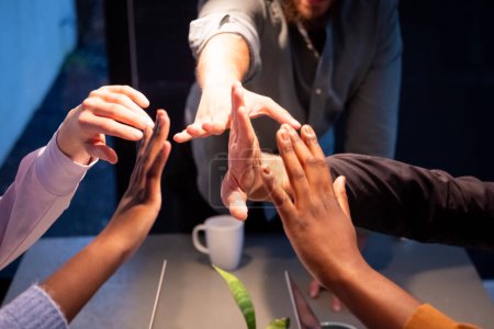 Photo for This image captures the hands of a professional team mid-celebration, giving a high five in a show of unity and success. The photo includes diverse team members, represented by a variety of skin - Royalty Free Image
