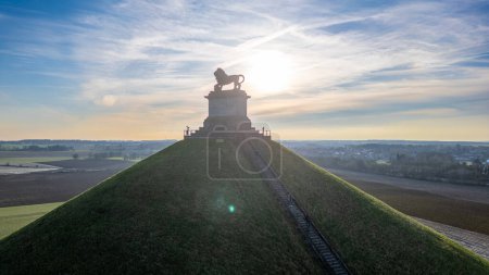 Photo for Waterloo, Brussels, Belgium, February 25th, 2024, This is a serene sunrise photograph of the Lions Mound at the Waterloo Battlefield memorial. The rising sun creates a radiant halo around the lion - Royalty Free Image