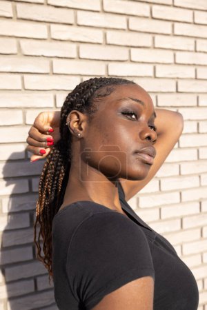 Aufgenommen in einem Moment der stillen Ruhe, zeigt dieses Foto eine junge Afrikanerin mit sanft geschlossenen Augen, die Ruhe ausstrahlt. Das Sonnenlicht streichelt ihre Haut und betont subtil ihr Gesicht