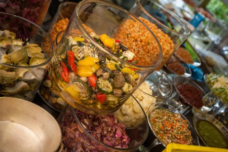 Dieses Bild zeigt ein üppiges Buffet mit einer Reihe frischer, farbenfroher Salate in großen Glasschalen, die eine Vielzahl von Texturen und Zutaten aufweisen und die Gäste zu einem Festmahl einladen.