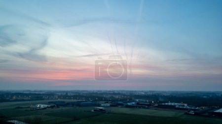 This serene image captures the quiet of early morning in the countryside, with a pastel sunrise stretching across the sky. The soft light brings a gentle awakening to the rural landscape, highlighting