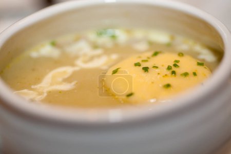 Dieses Bild zeigt eine Schüssel mit cremiger Kartoffelsuppe, deren reichhaltige Konsistenz von einem schmelzenden Stück Butter und einer Prise frischem Schnittlauch unterbrochen wird. Perfekt für eine wohltuende Mahlzeit verspricht die Suppe Wärme und