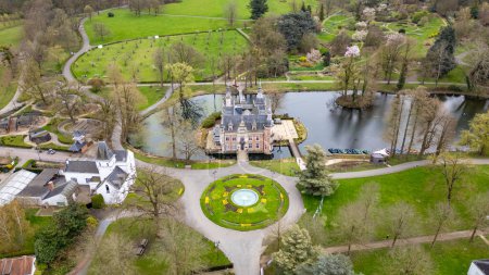 Foto de Huizingen, Bélgica, 26 de marzo de 2024, Capturada desde arriba, esta imagen presenta el castillo de Huizingen en todo su esplendor, rodeado de jardines bien cuidados y un estanque tranquilo. La vegetación ornamental y - Imagen libre de derechos